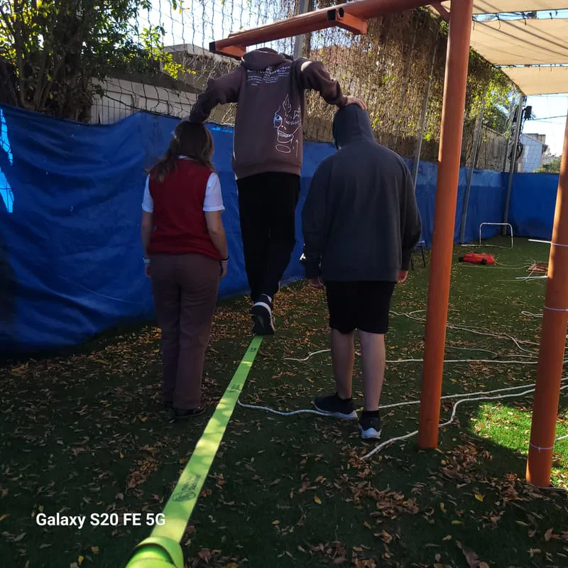 תלמיד עובר על רצועת סלקליין בעזרת חבריו במהלך פעילות גיבוש